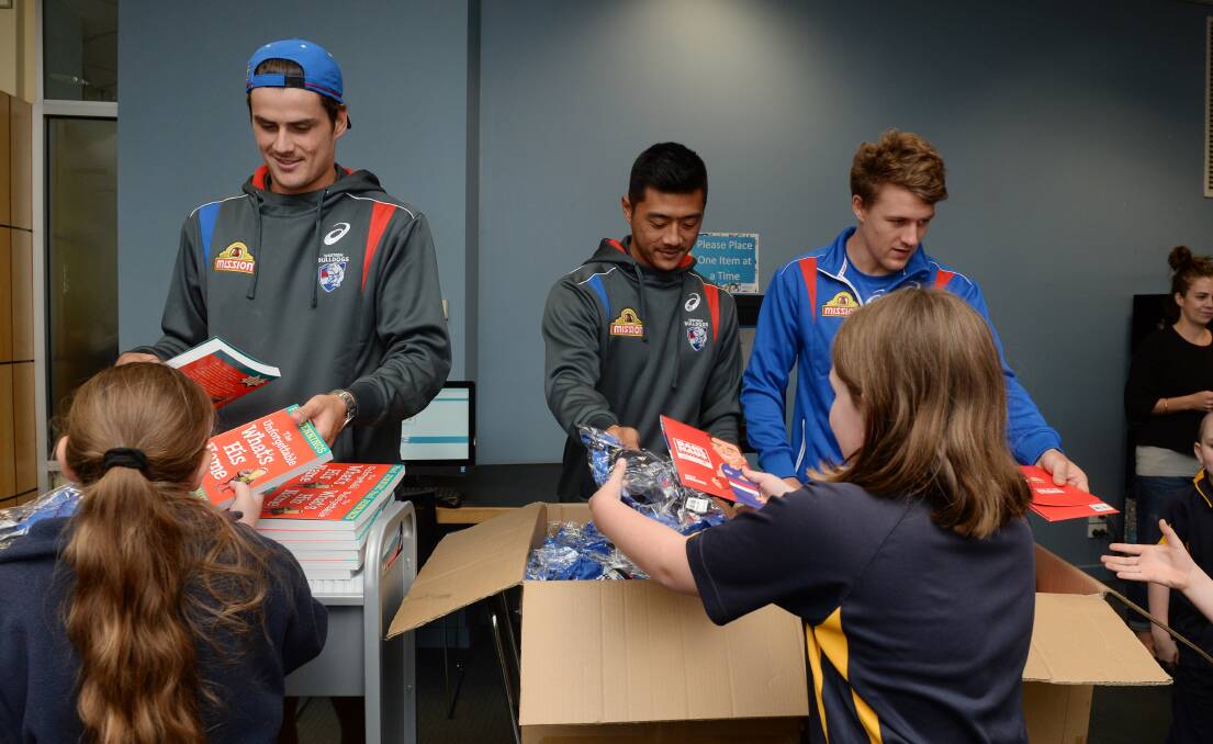 Bulldogs Tom Boyd, Lin Jong and Jack Macrae make sure Bulldogs Read participants are kitted-up for the program. Picture: Kate Healy