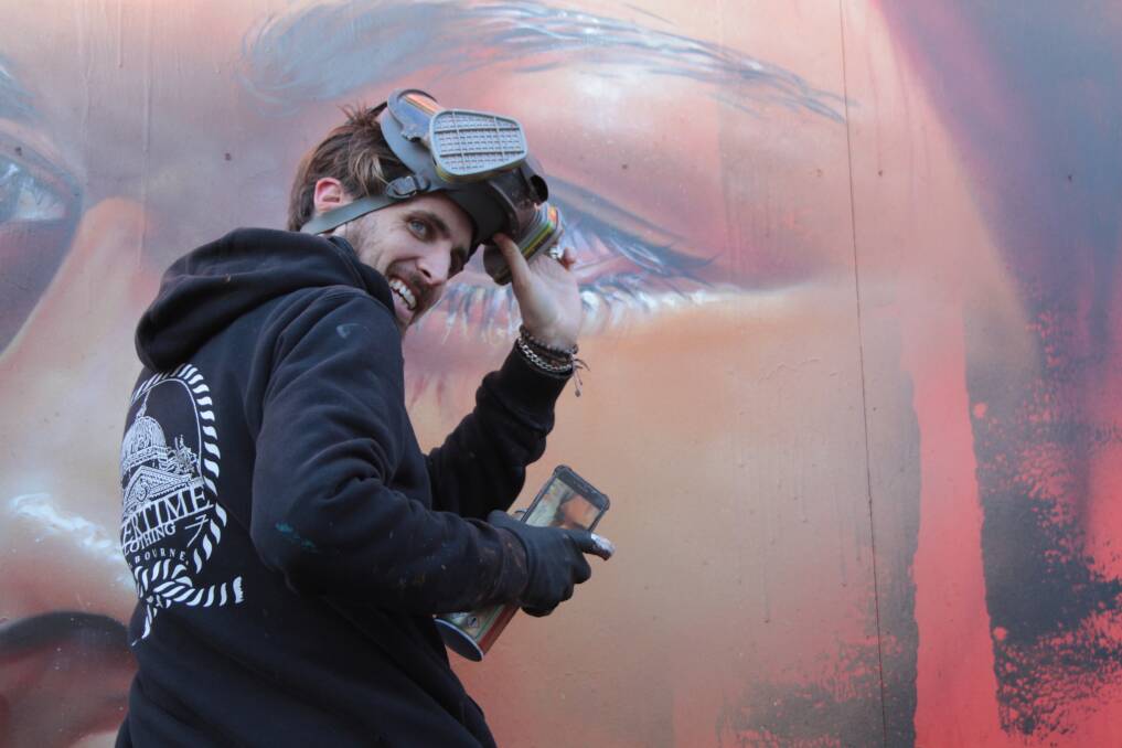 Finished piece: Artist Adnate puts the finishing touches on his piece in Trentham, which is a portrait of indigenous woman Akira Kelly.  Picture: Richard Ryan.  