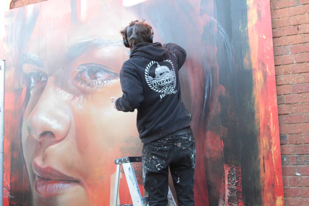 Hard at work: Renowned artist Adnate working on the 2.4x3.6 metre mural in Trentham on the weekend.  The spectacle drew almost 200 onlookers to the town.  Picture: Richard Ryan.