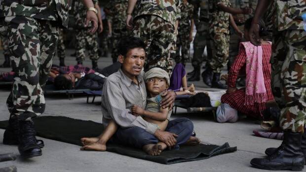 A man sits with a child on his lap as victims of Saturday's earthquake wait for ambulances after being evacuated to Kathmandu, Nepal. Photo: AP