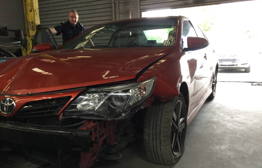 Police inspect the recovered orange Toyota.