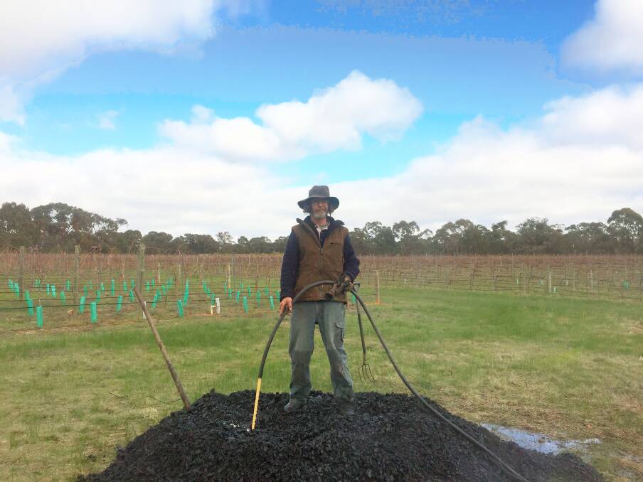 King of the hill: Wynne stands on the cooled pile of biochar he and Shane Mead have just created from unwanted waste of Quartz Hill vineyard. Mead will mix the char with emulsion and spread it through his vines. Picture: Caleb Cluff.
