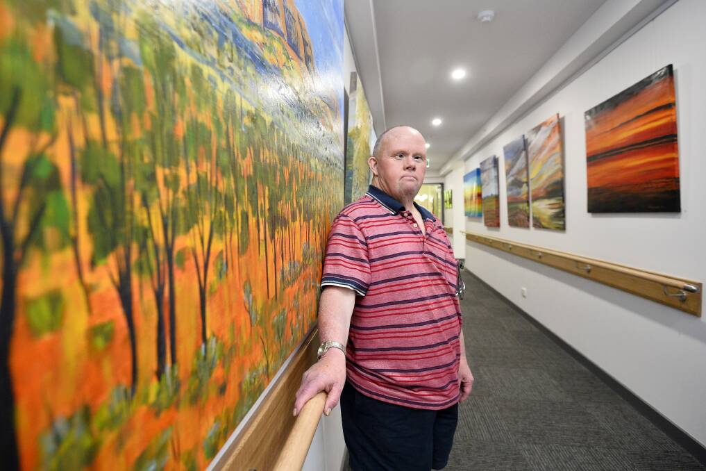 ART EXHIBITION: John Curtin Aged Care resident Michael Forde stands next to one of Steve Bruechert's pieces which features in the centre's art exhibition. 