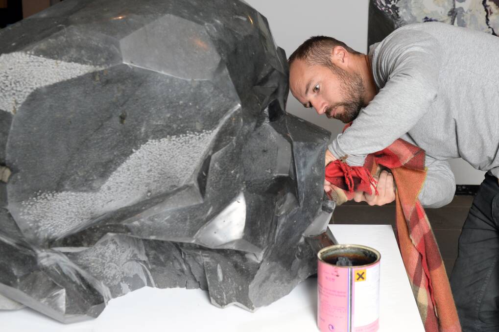 Josh Bowes polishes his basalt skull on exhibition at the Art Gallery of Ballarat. Picture: Kate Healy