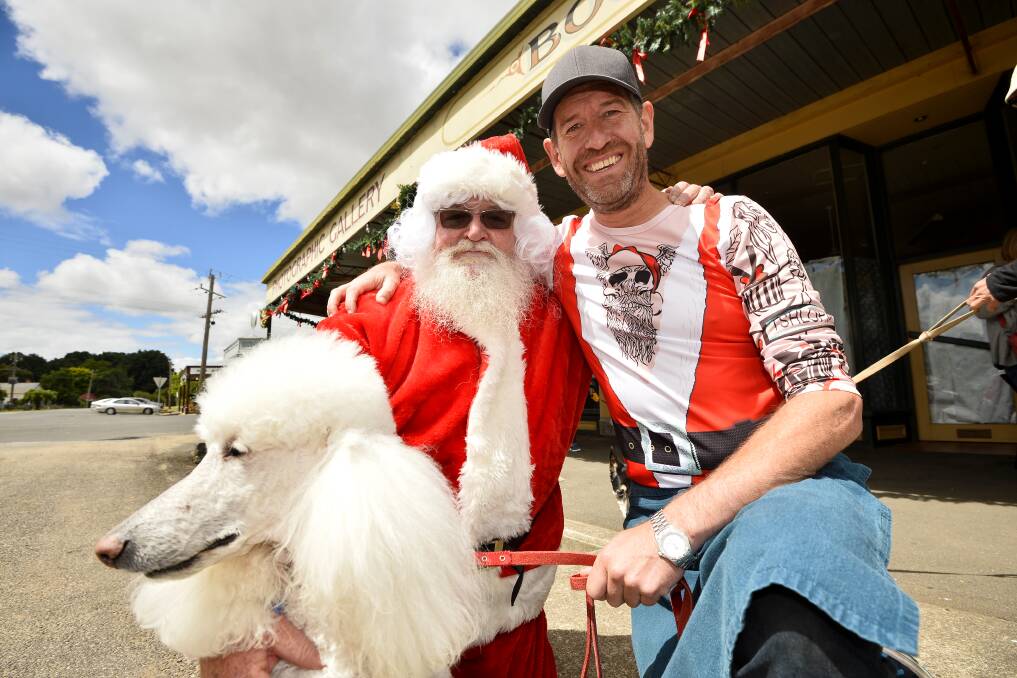 WOOF: Quigley and Clarke owner Steven Hunter and Santa Claus and his four-legged friend celebrate Christmas in Clunes on Friday. Picture: Dylan Burns