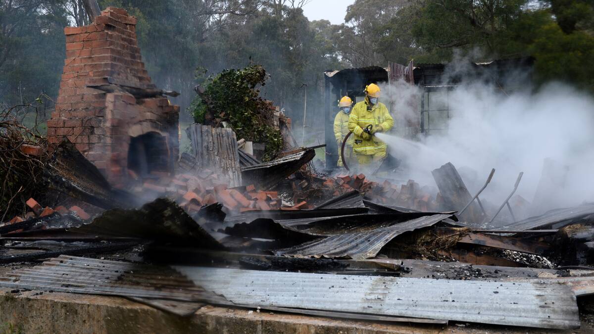 RAZED: Firefighters investigate the vacant miner’s cottage in Creswick that was destroyed by fire over the weekend. 