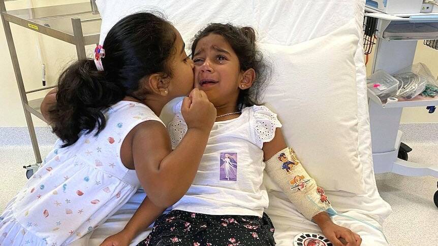 Kopika, left, comforting sister Tharnicaa in hospital on Christmas Island. The family have now been taken to Perth. Picture: Supplied